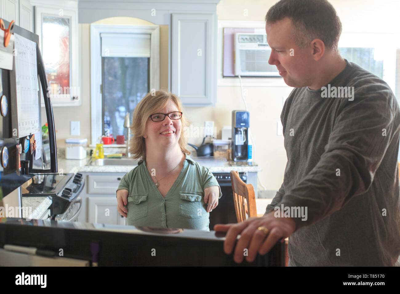 Donna con sindrome di catrame e suo marito usando il proprio computer a casa Foto Stock