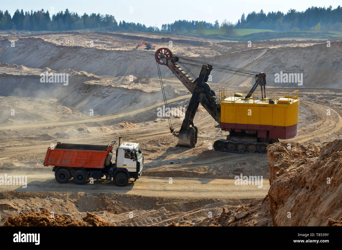 Autocarro con cassone ribaltabile in data mining industriale di cava. L'escavatore carichi sabbia in una pesante camion per il trasporto all'impianto di frantumazione e spedizione di sor Foto Stock