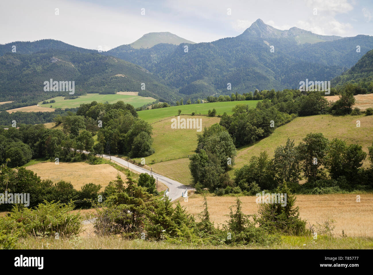 Una valle tra le montagne, i campi e le aziende agricole e le montagne in distanza. Foto Stock