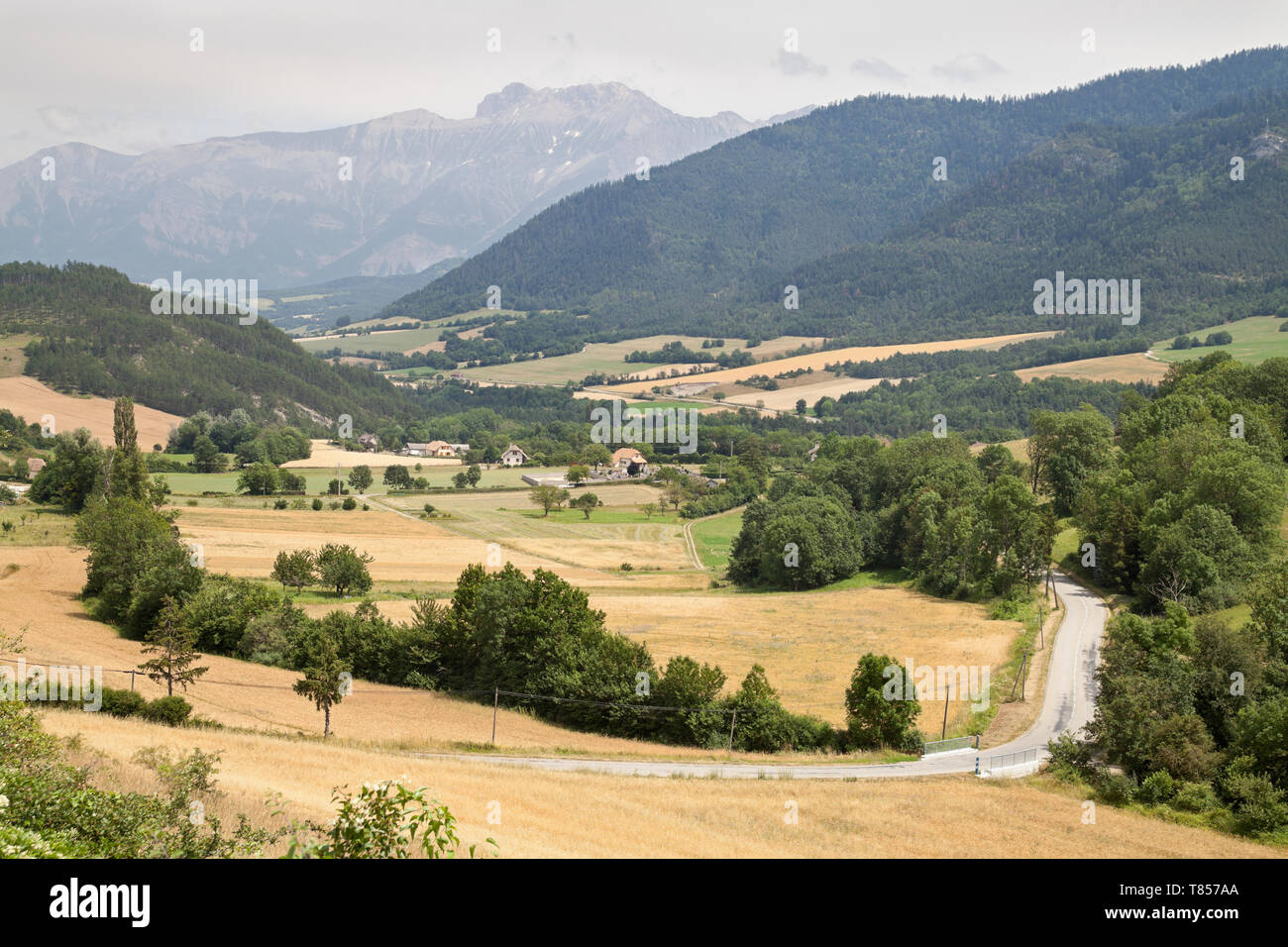 Una valle tra le montagne, i campi e le aziende agricole e le montagne in distanza. Foto Stock
