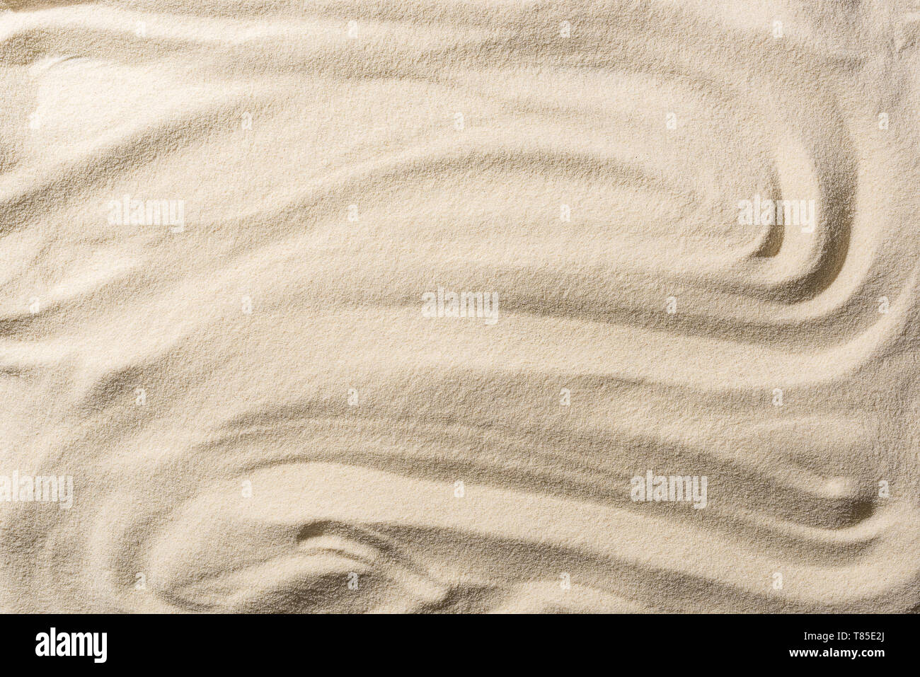 Vista superiore della sabbia testurizzata sfondo beige con onde lisce Foto Stock