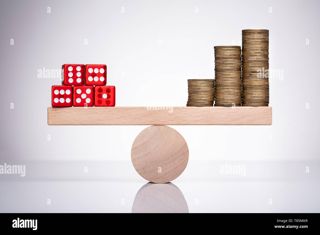 Dadi rossi Stack e denaro monete in equilibrio su una altalena Foto Stock