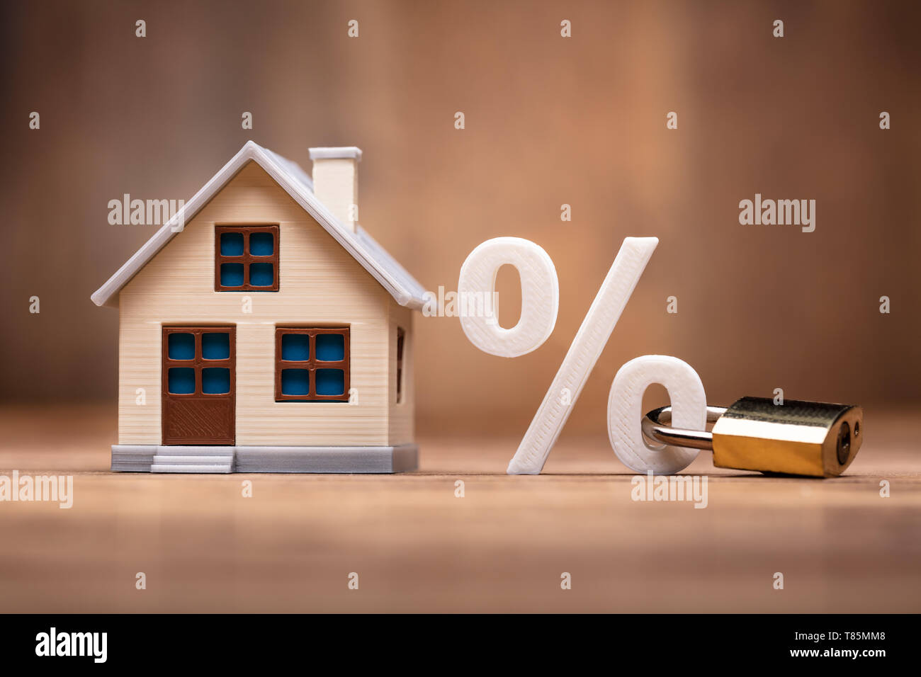 Modello di casa vicino al segno di percentuale con il blocco della tastiera sulla scrivania in legno Foto Stock