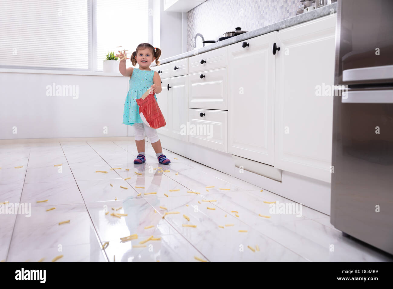 Ragazza sorridente gettando le patatine fritte in cucina Foto Stock