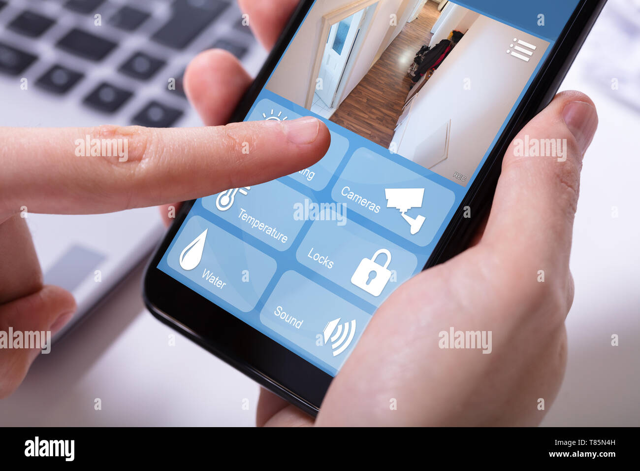 Close-up di un imprenditore il canto servendosi di un sistema di sicurezza domestica sul telefono cellulare Foto Stock