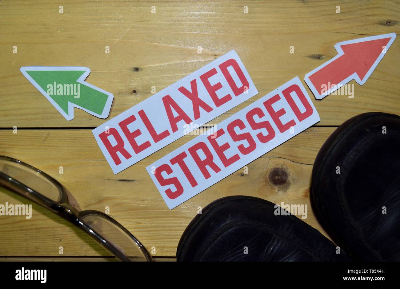 Rilassati o sollecitato in direzione opposta i segni con scarponi e occhiali su legno sfondo vintage. Business, Education Finance e concetti Foto Stock