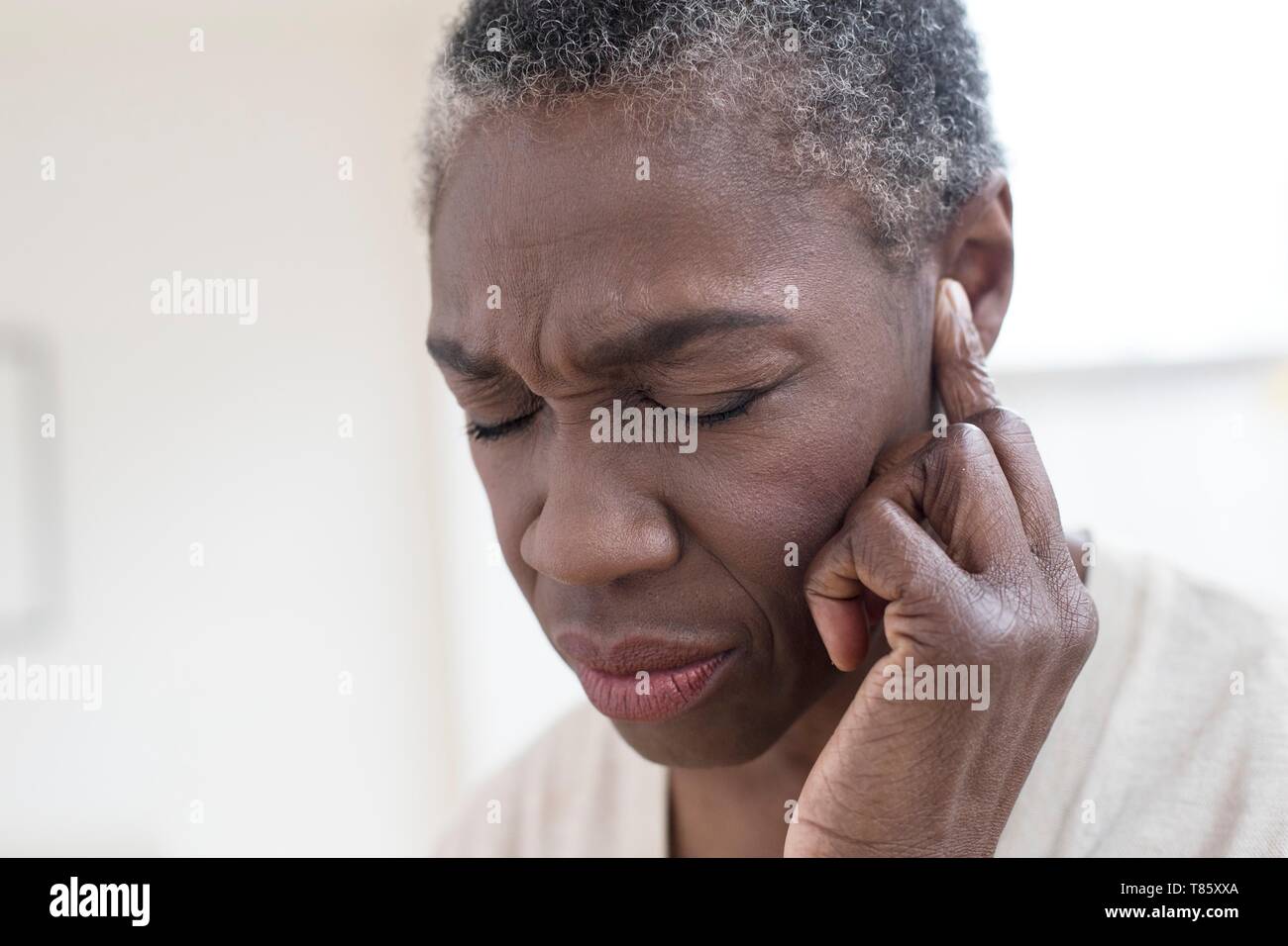 Donna toccando orecchio Foto Stock