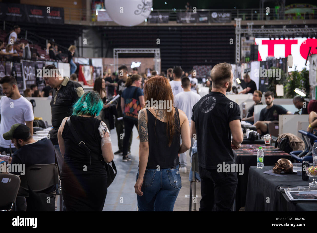 Si vedono persone a piedi e guardare il tatuaggio gli artisti fanno il loro lavoro durante il festival. Migliaia di tatuaggio di artisti di tutto il mondo hanno preso parte nel corso della XIII Athens International Tattoo Convention e hanno anche fatto tatuaggi a coloro che erano interessati. Foto Stock