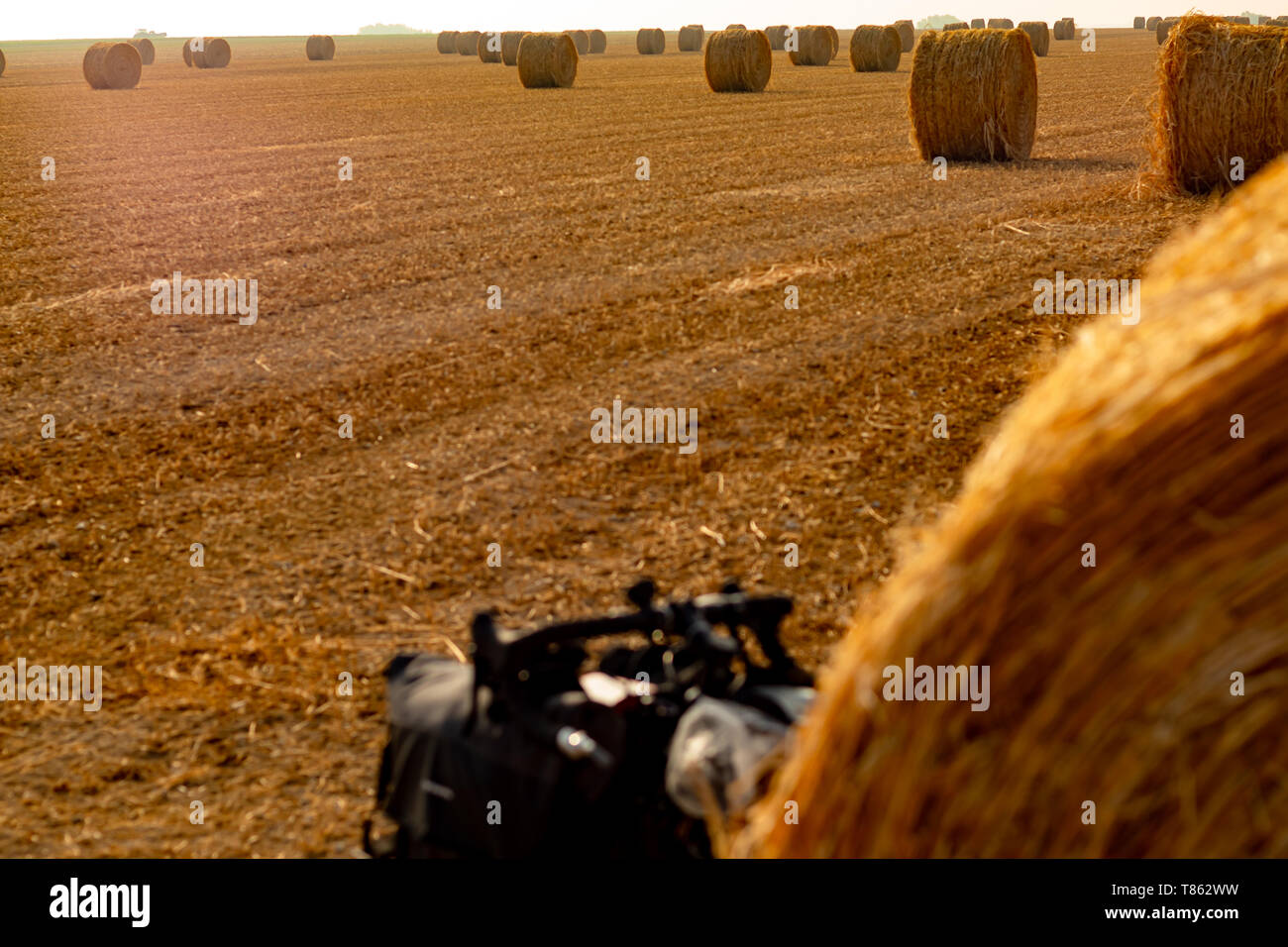 Touring bike nascosto dietro una palla di fieno in un grande orangee-campo colorato Foto Stock