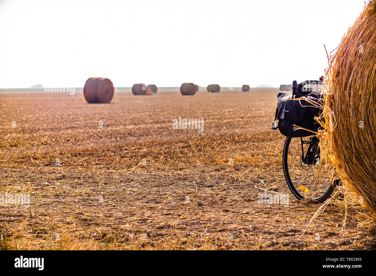 Touring bike nascosto dietro una palla di fieno in un grande orangee-campo colorato Foto Stock