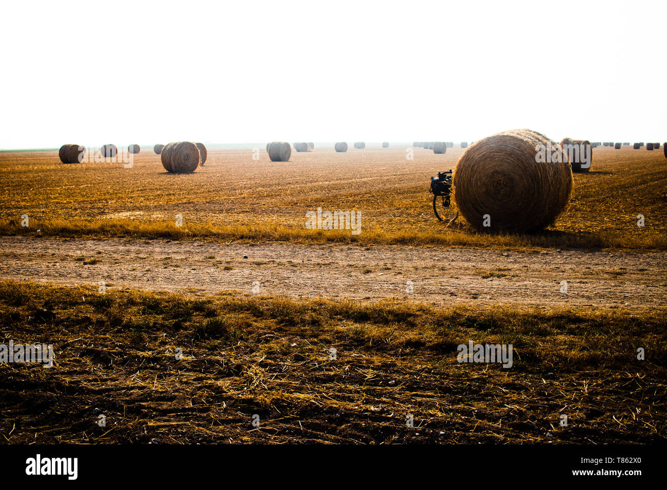 Touring bike nascosta da una palla di fieno in un grande orangee-campo colorato Foto Stock