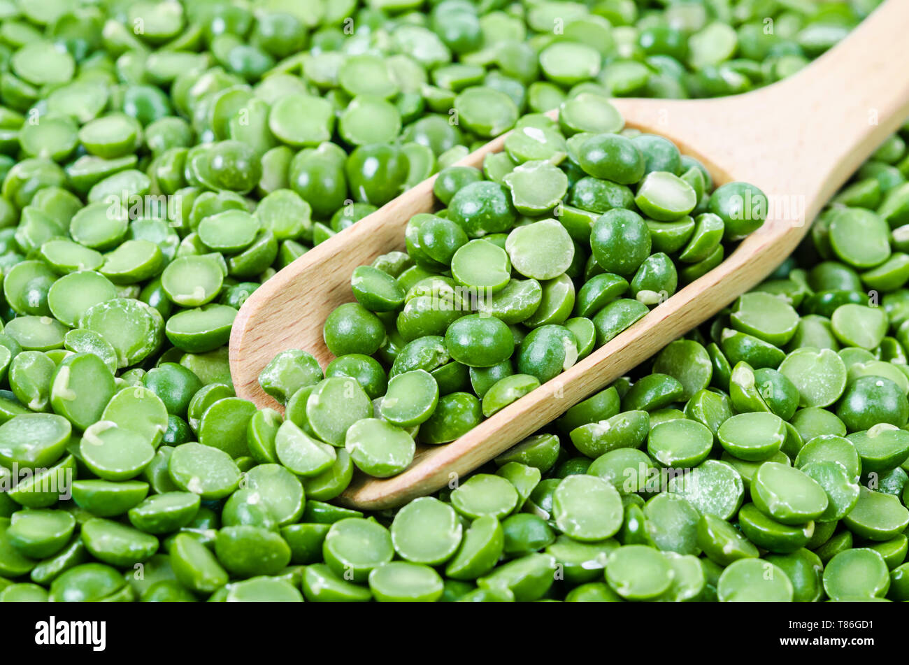 Verde di piselli secchi con il cucchiaio di legno. Ingrediente di cottura. Foto Stock