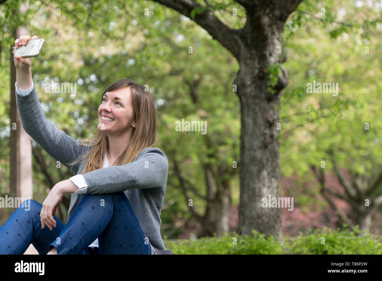 Attraente donna millenaria nel parco, vivere e godere la vita, guardando come uno stile di vita ad Foto Stock