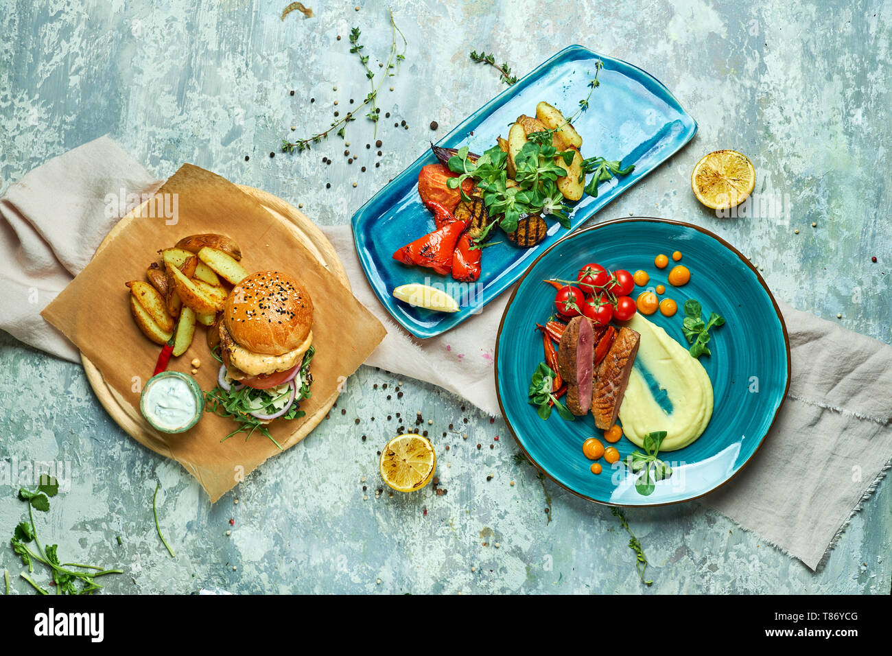 Tre piatti con hamburger di carne con verdure grigliate svrhu vista su sfondo grigio Foto Stock