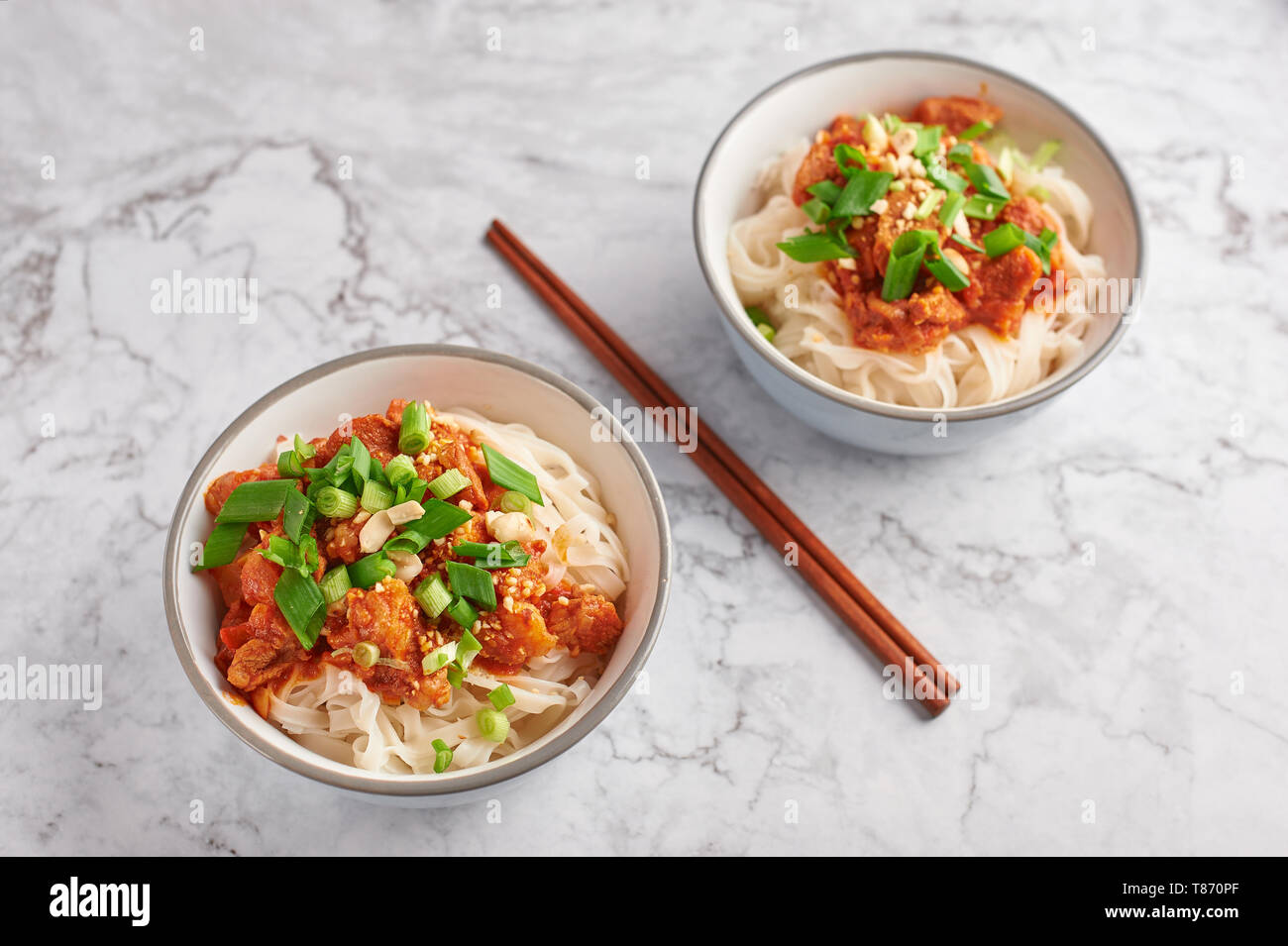 Shan tagliatelle con bacchette in marmo bianco del piano portapaziente. cucina birmana piatto tradizionale. myanmar cibo. spaghetti di riso con carne di maiale in pomodori. piatto asiatico Foto Stock