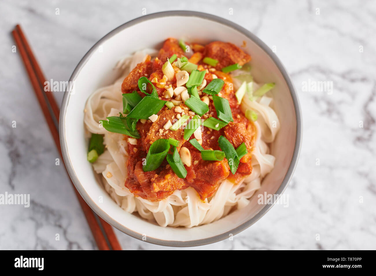 Shan tagliatelle con bacchette in marmo bianco del piano portapaziente. cucina birmana piatto tradizionale. myanmar cibo. spaghetti di riso con carne di maiale in pomodori. piatto asiatico Foto Stock