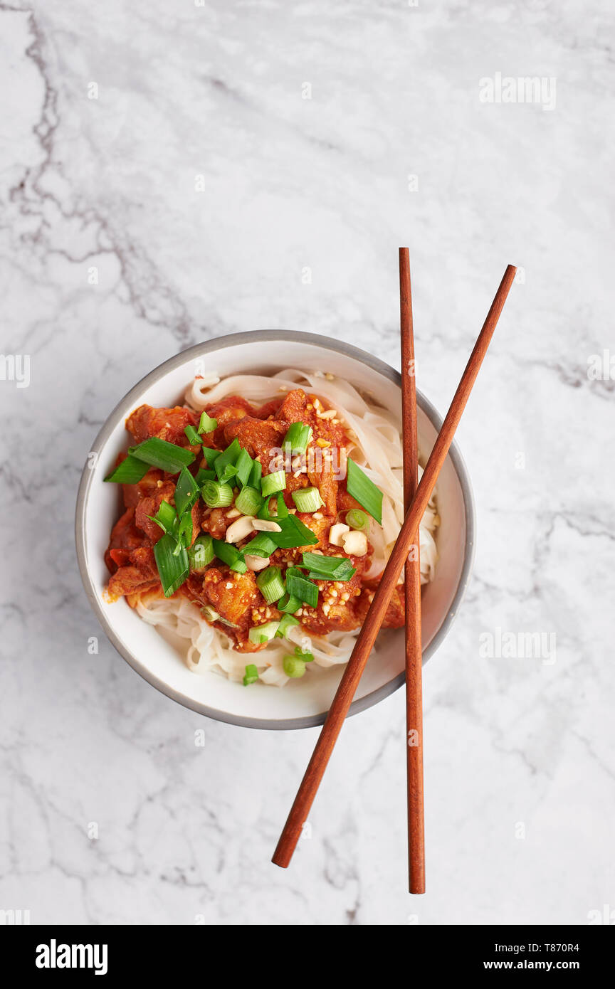 Shan tagliatelle con bacchette in marmo bianco del piano portapaziente. cucina birmana piatto tradizionale. myanmar cibo. spaghetti di riso con carne di maiale in pomodori. piatto asiatico Foto Stock