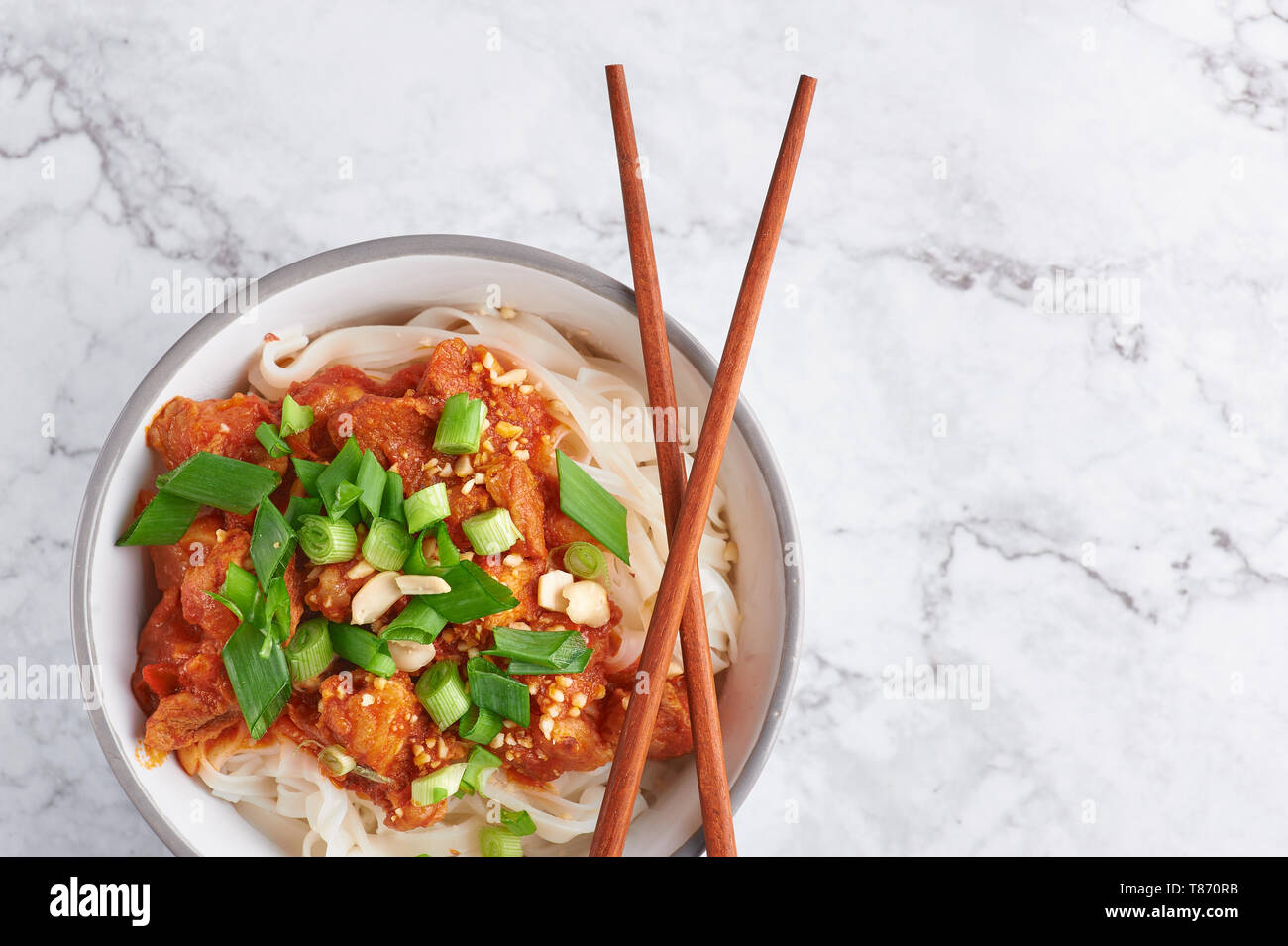 Shan tagliatelle con bacchette in marmo bianco del piano portapaziente. cucina birmana piatto tradizionale. myanmar cibo. spaghetti di riso con carne di maiale in pomodori. piatto asiatico Foto Stock