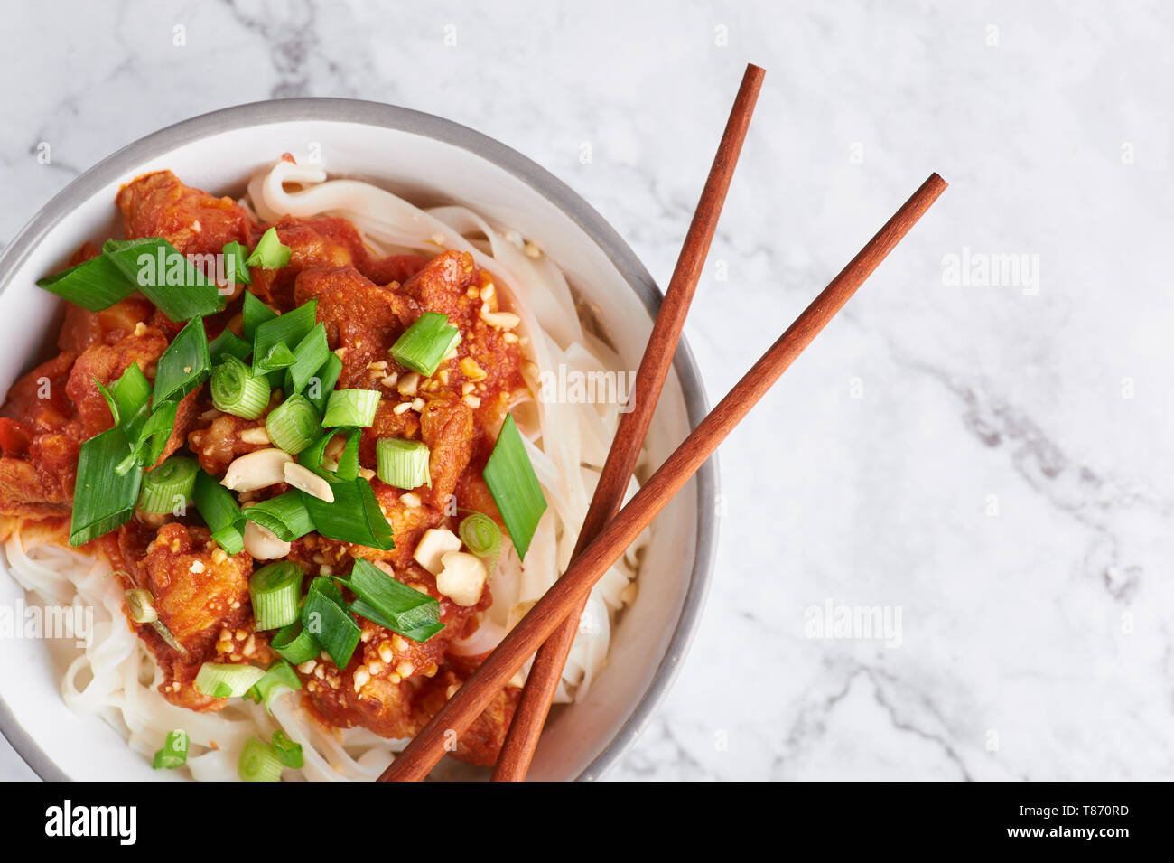 Shan tagliatelle con bacchette in marmo bianco del piano portapaziente. cucina birmana piatto tradizionale. myanmar cibo. spaghetti di riso con carne di maiale in pomodori. piatto asiatico Foto Stock