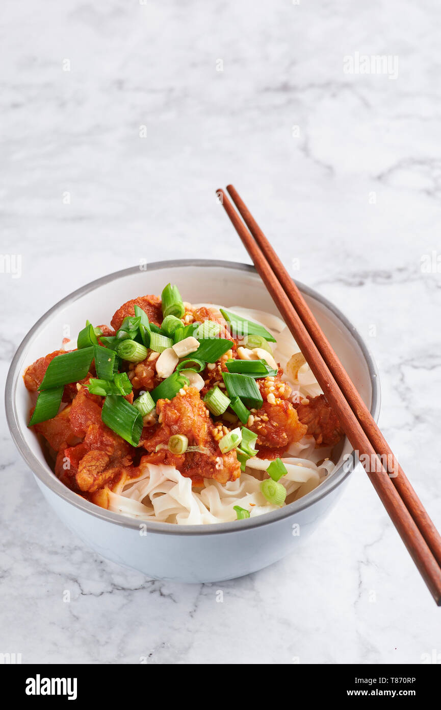 Shan tagliatelle con bacchette in marmo bianco del piano portapaziente. cucina birmana piatto tradizionale. myanmar cibo. spaghetti di riso con carne di maiale in pomodori. piatto asiatico Foto Stock