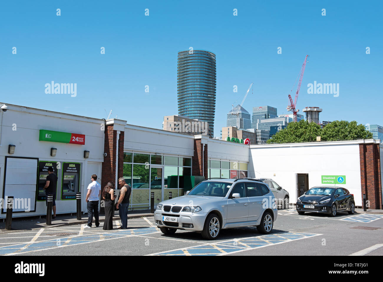 ASDA prelievi dagli ATM macchina con persone di accodamento, parcheggio auto Crossharbor, Isle of Dogs, London Borough of Tower Hamlets. Foto Stock