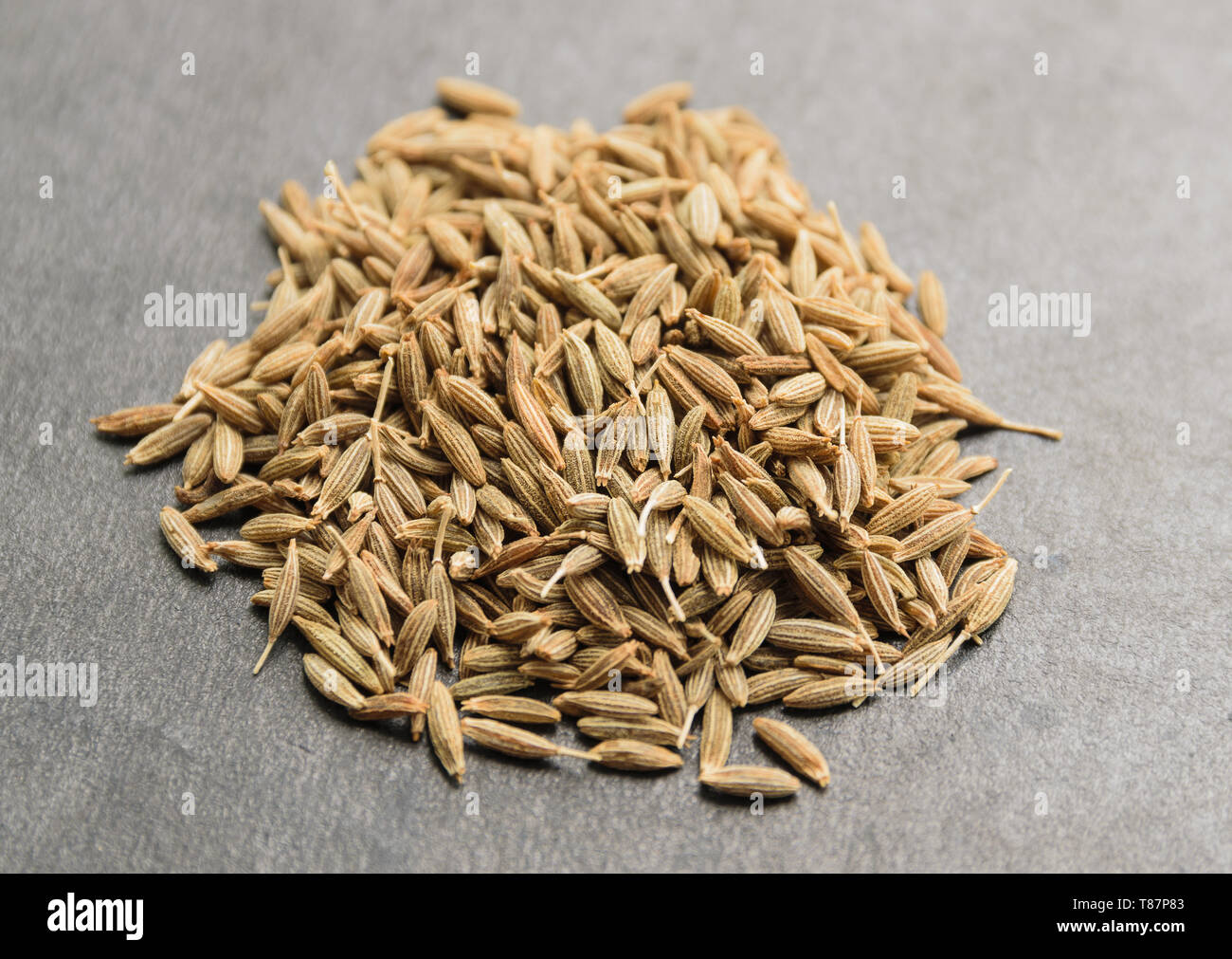 Pila di semi di cumino su sfondo scuro. Macro con profondità di campo ridotta. Foto Stock