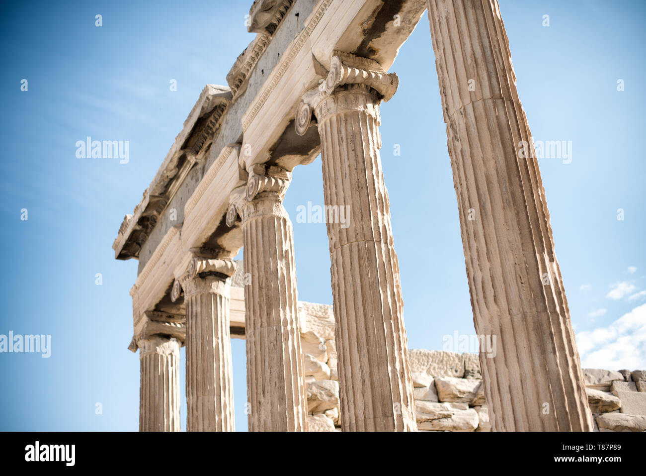 Colonne ioniche contro il cielo sull'Acropoli | ATENE — Una vista a bassa angolazione ad Atene isola gli steli dorici scanalati e i capitelli ionici del Partenone contro un cielo sereno sopra l'Acropoli. Completato nel 432 a.C. sotto Pericle, le colonne del tempio erano affusolate e curve verso l'esterno, un raffinamento chiamato entasi, così che i loro lati appaiano perfettamente dritti all'occhio dal livello del suolo. Foto Stock