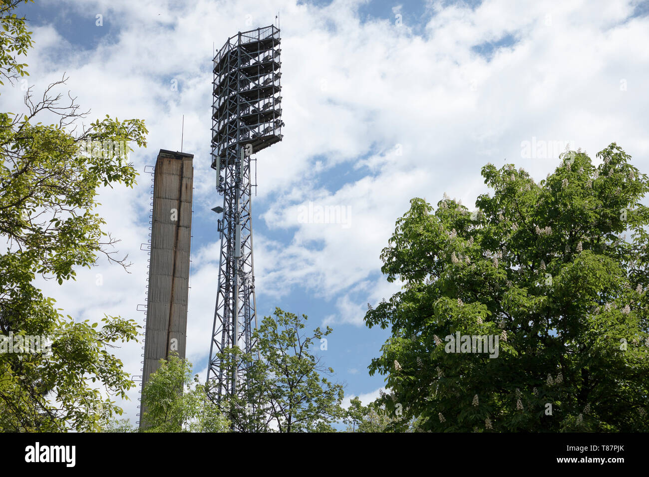 Luci di alto standing per illuminare un campo di calcio. Sparato contro il cielo blu. Luci a uno stadio sportivo. Foto Stock