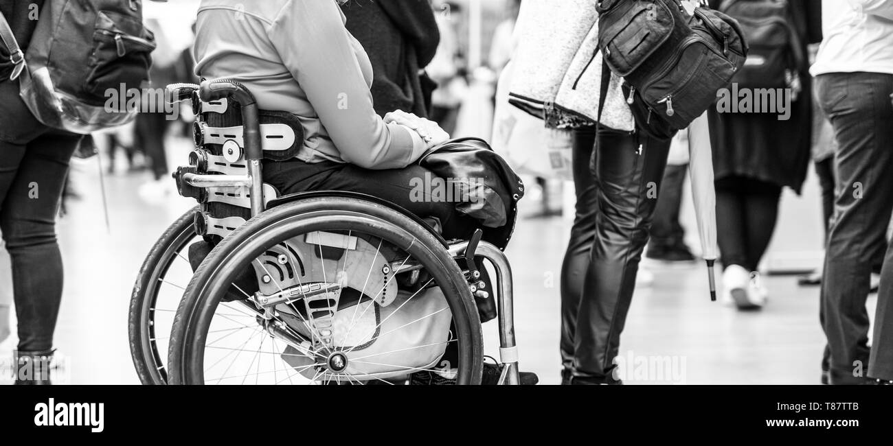 Close up di un irriconoscibile hanicapped donna su una sedia a rotelle in coda in linea per eseguire le attività quotidiane. Foto Stock