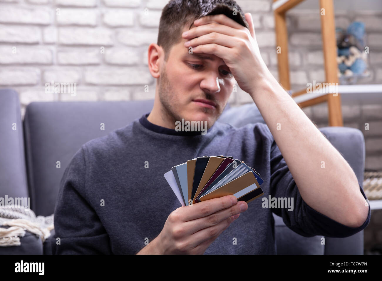 Ha sottolineato l'uomo Guardando troppo molte carte di credito in Home Foto Stock