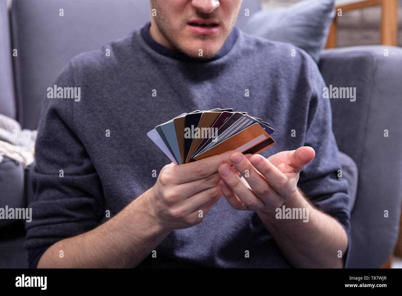 Ha sottolineato l'uomo Guardando troppo molte carte di credito in Home Foto Stock