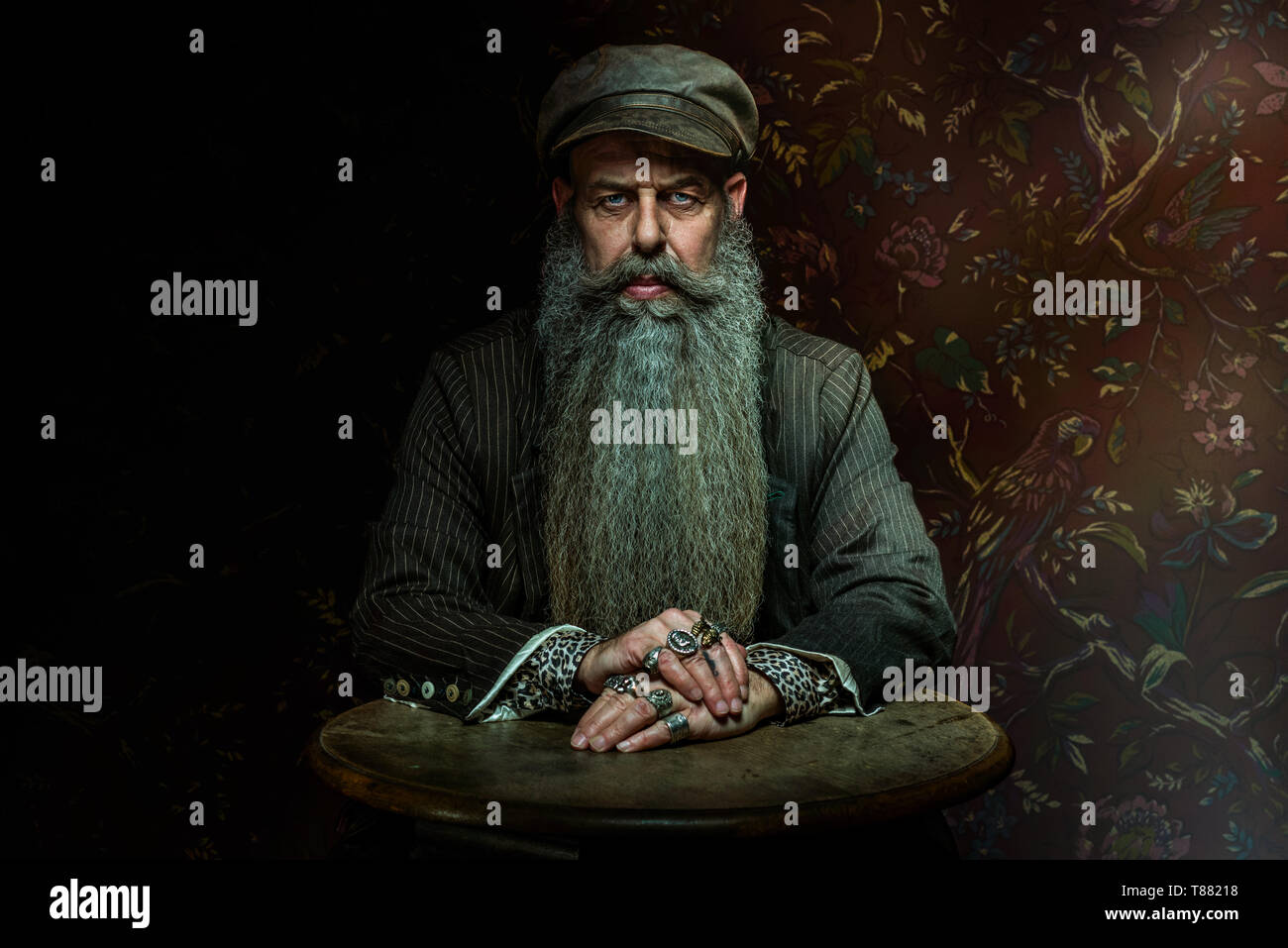 Uomo seduto a tavola con la barba lunga Foto Stock