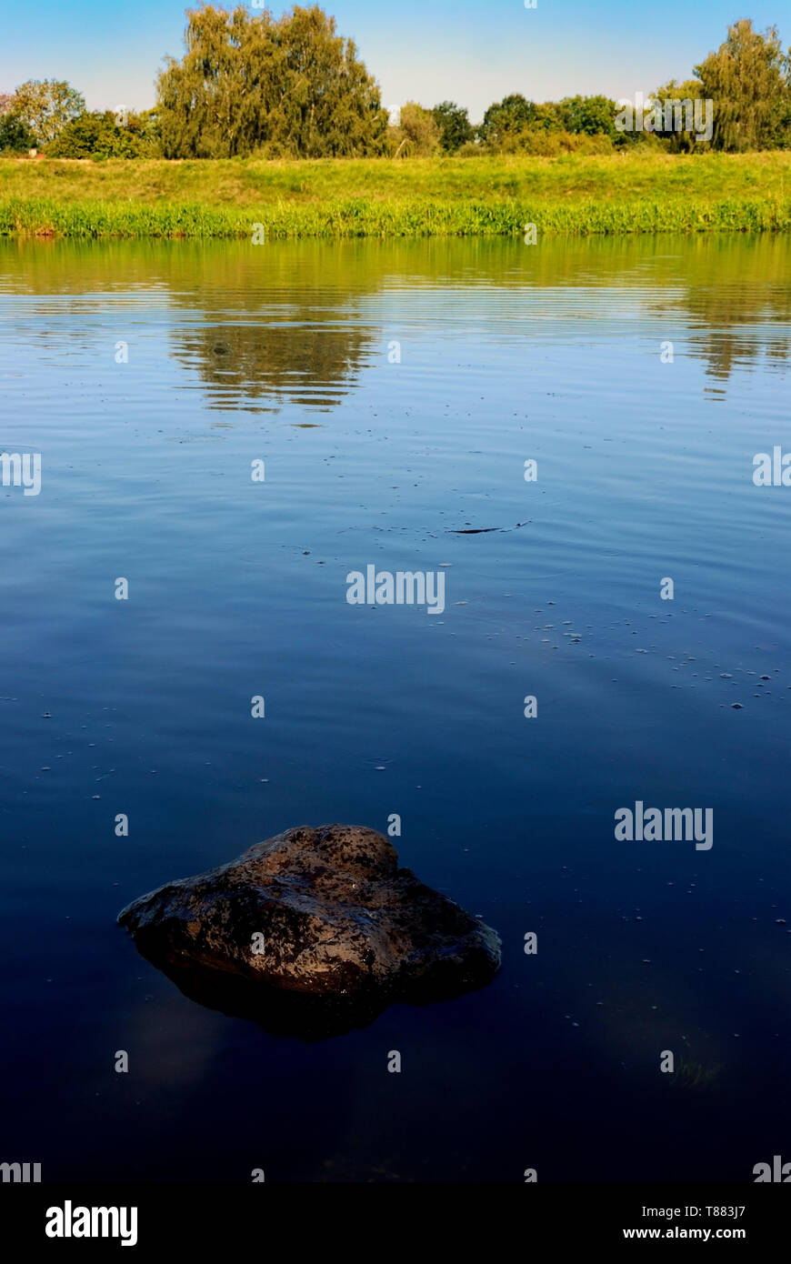 La vista sul fiume dal suo banche con alberi e cielo blu in background Foto Stock