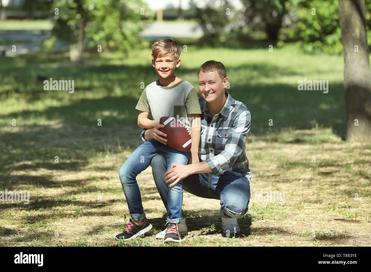 Felice di padre e figlio con il pallone da rugby in posizione di parcheggio Foto Stock