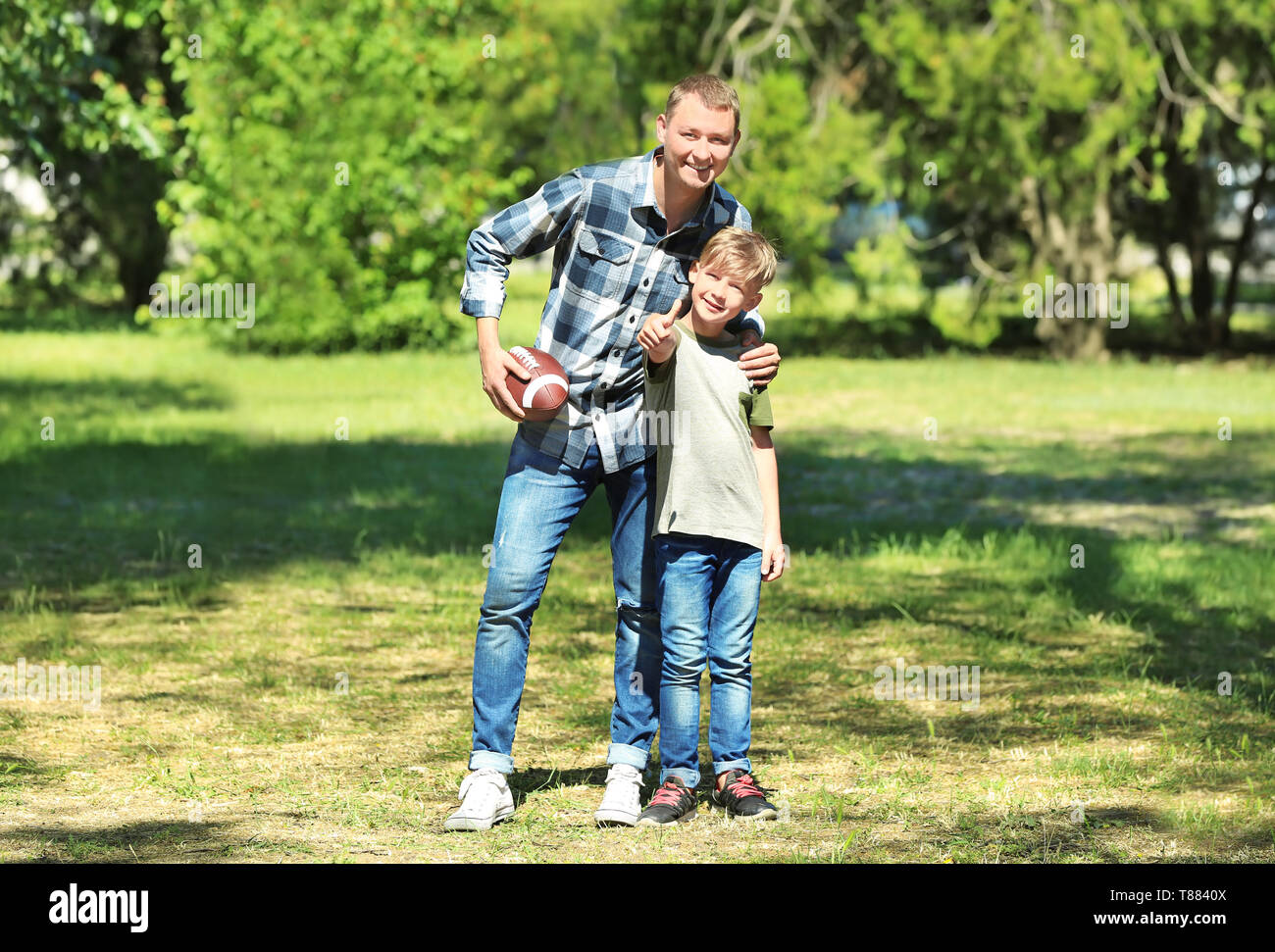 Felice di padre e figlio con il pallone da rugby in posizione di parcheggio Foto Stock