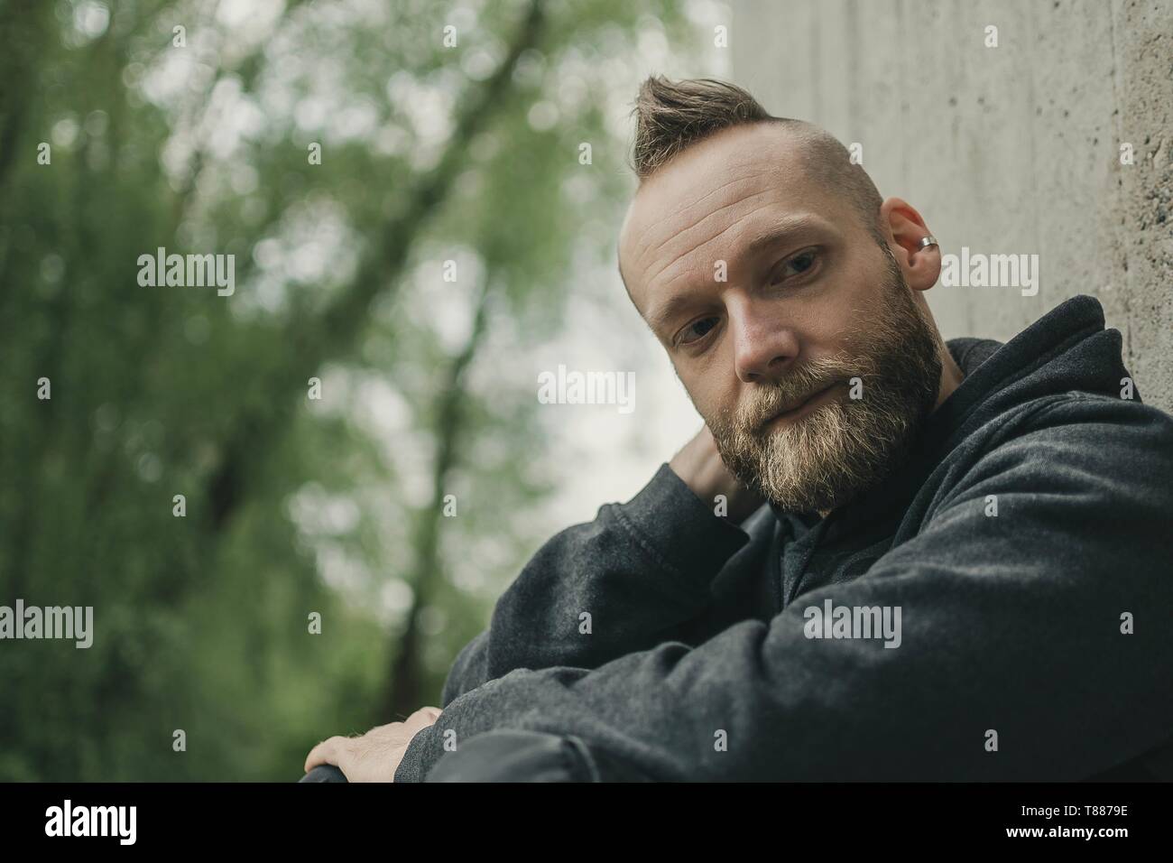 Felice soddisfatto giovane uomo seduto per terra e di pensiero Foto Stock