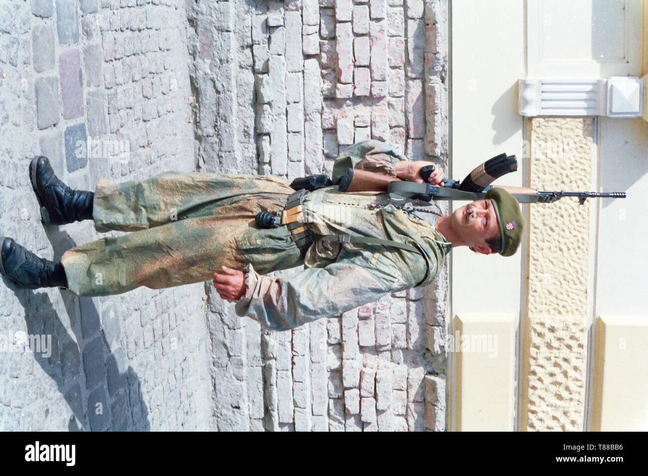 Un paracadutista croato pone per la fotocamera nella città merlata di Osijek nella ex Jugoslavia durante il conflitto nel 1991-1992. Foto di Adam Alexander Foto Stock