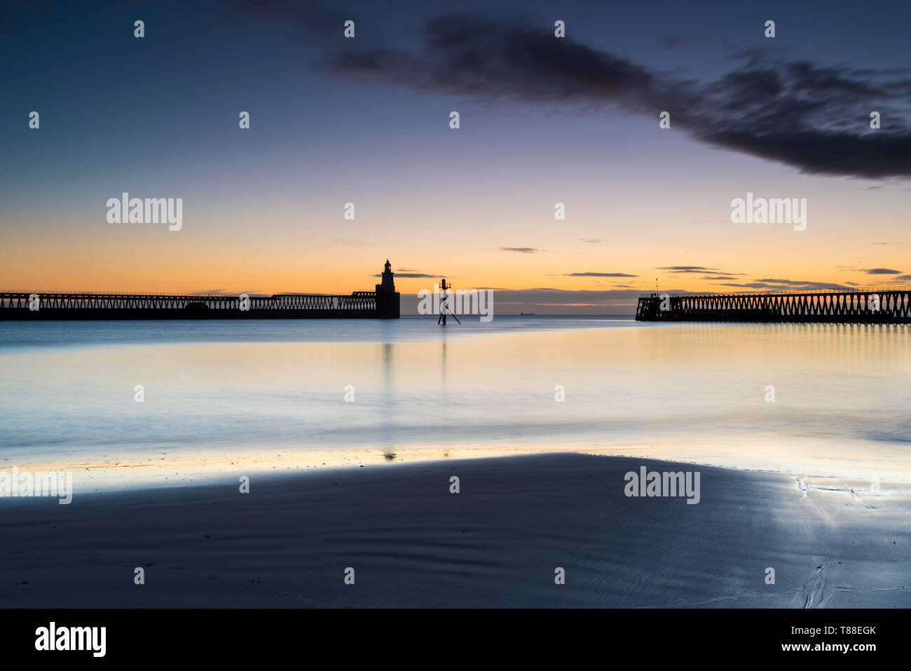 Inizio inverno freddo mattino per catturare la orange sunrise che sagome di Blyth banchine portuali & Porto Faro in Northumberland Foto Stock