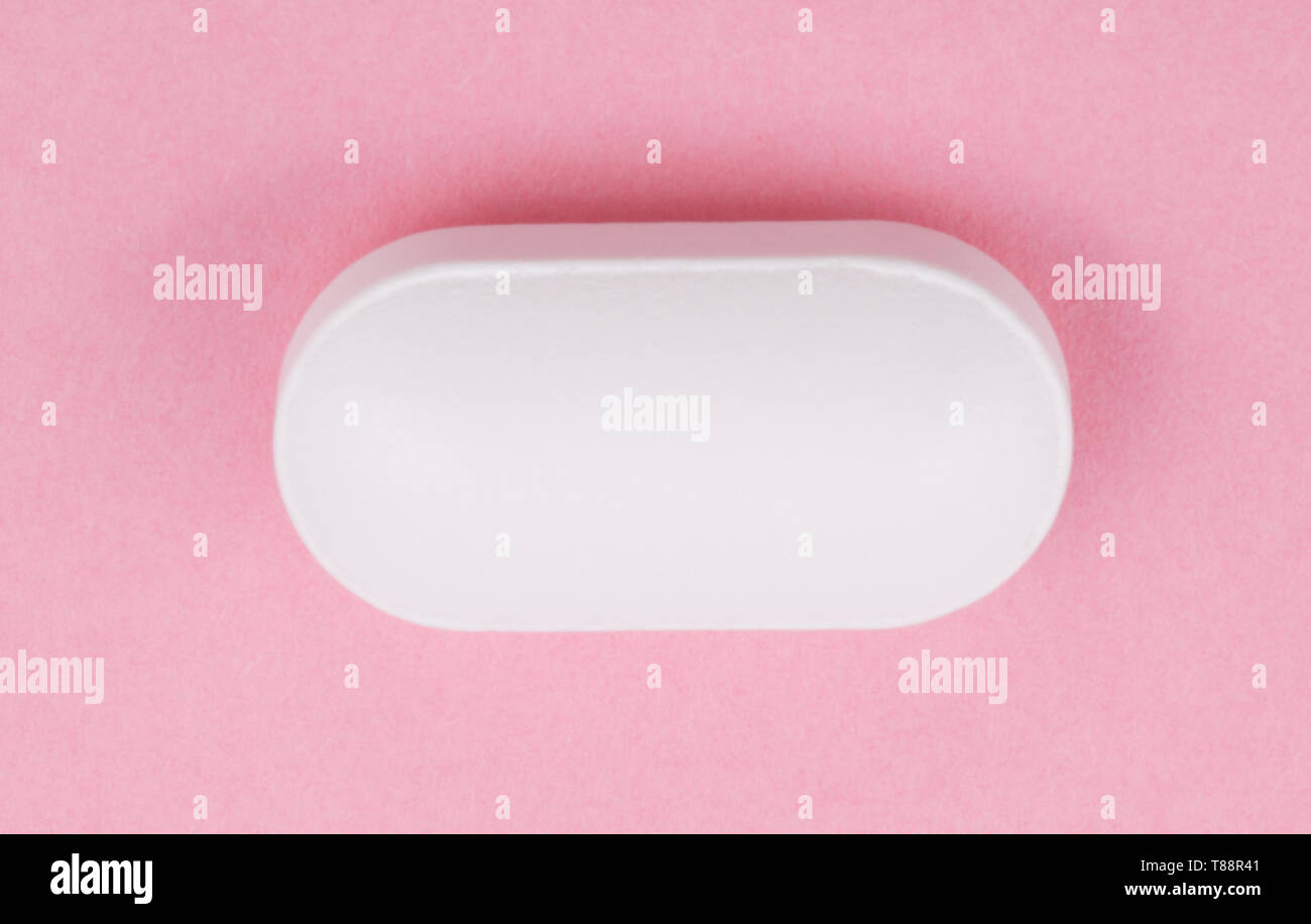 Pillola bianco su sfondo rosa Foto Stock