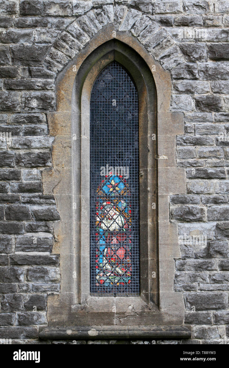 Restringere la finestra della chiesa che mostra il vetro macchiato al di là. Pareti di pietra. Foto Stock