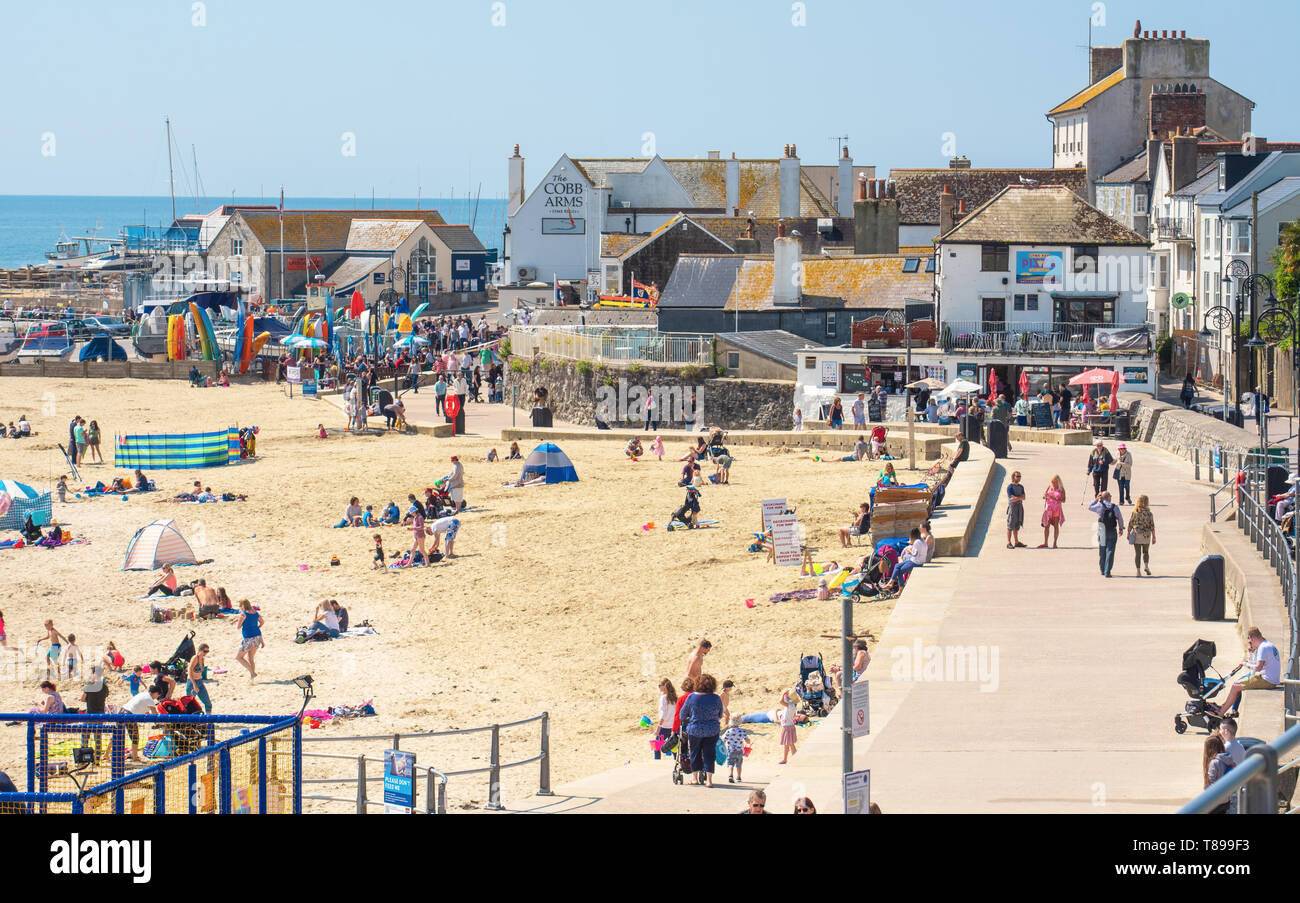 Lyme Regis, Dorset, Regno Unito. Il 12 maggio 2019. Regno Unito: Meteo visitatori e amanti di spiaggia godetevi la pittoresca spiaggia presso la località balneare di Lyme Regis su una calda e soleggiata domenica. Le temperature sono dilagano con alti di 25 gradi celsius previsioni per la prossima settimana. Credito: Celia McMahon/Alamy Live News. Foto Stock