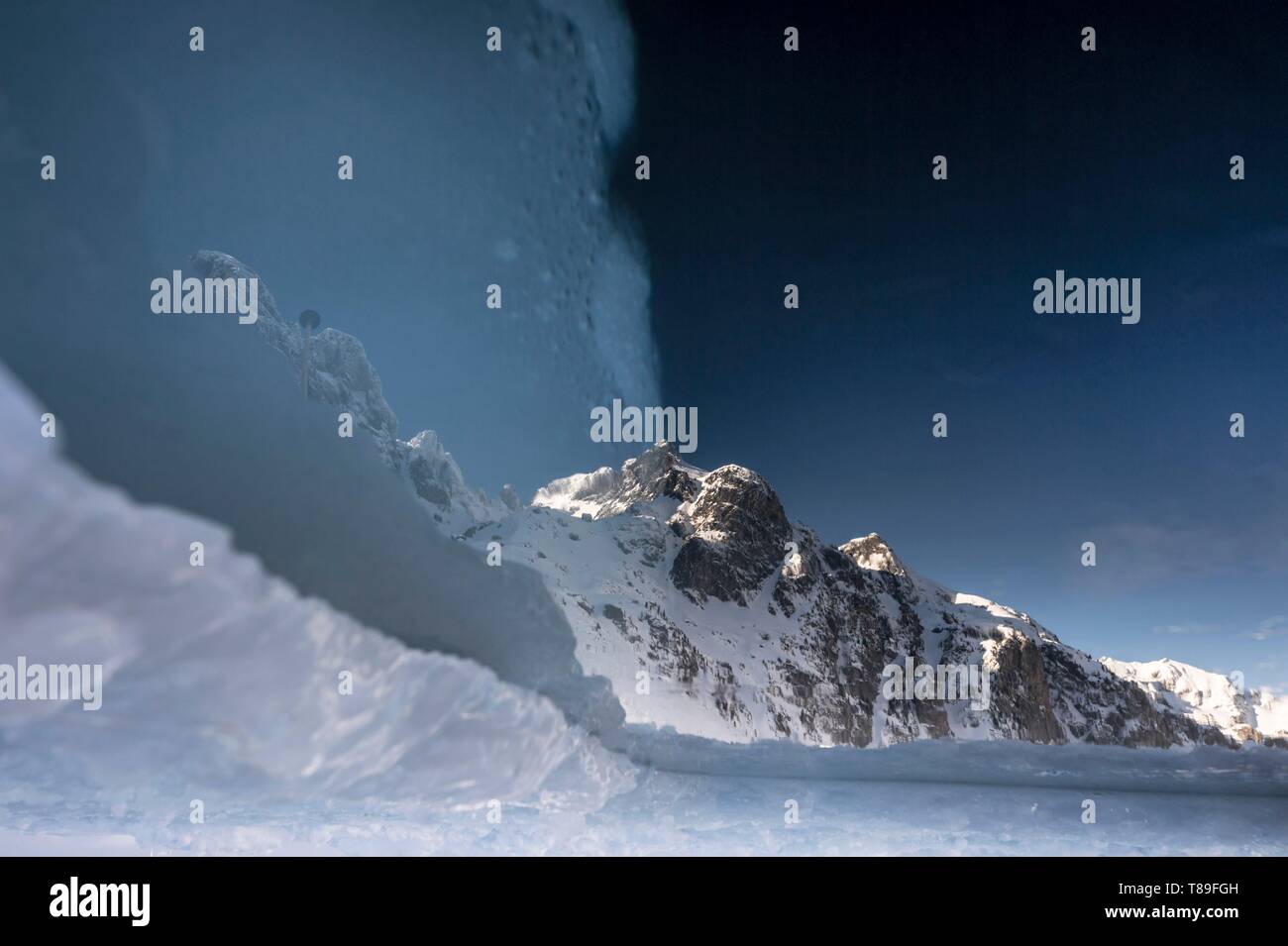 In Francia, in Isère (38), Belledonne, Chamrousse, Robert laghi bordati e dominata ad est da Petit Van (2,439 metri), Grand Van (2,448 metri) e Grand Sorbier (2,526 metri), riflettendo le cime della montagna attraverso un foro scavato nel ghiaccio per consentire immersioni subacquee Foto Stock