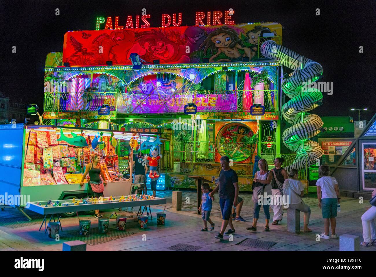 Francia, Herault, Sete, parte) di Saint-Pierre, famiglia passando davanti ofa merry-go-round illuminata di notte Foto Stock