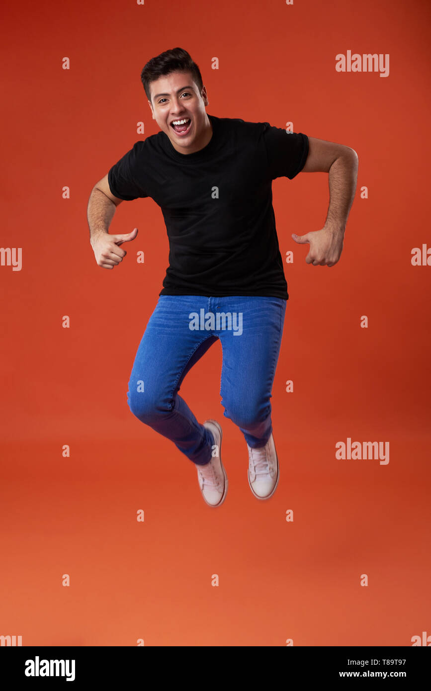 Giovane uomo saltando su sfondo colorato e punto di t-shirt Foto Stock