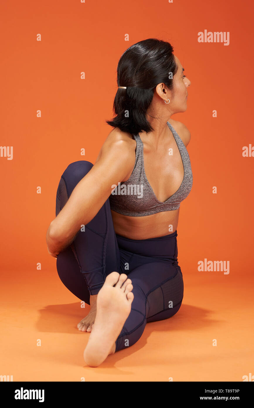 Marichi la vista frontale dello yoga donna posa dimostrare su orange il colore di sfondo per studio Foto Stock