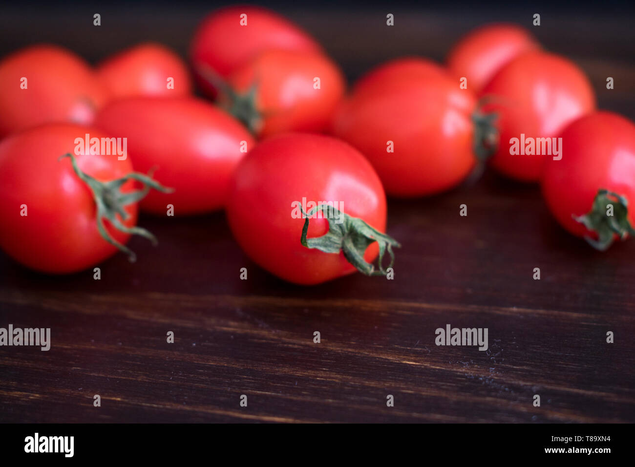 Pomodori uva al buio su un sfondo di legno Foto Stock