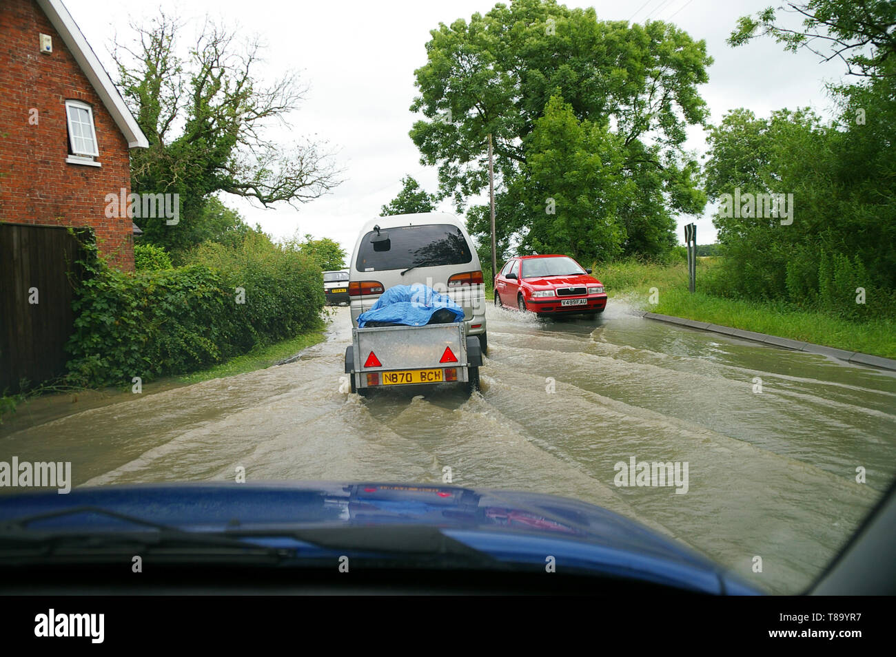 Guidare attraverso strade allagate di auto. Vista del conducente dall'interno dell'auto guidata attraverso le inondazioni di acqua piovana nella strada di campagna del Lincolnshire vicino all'hotel. Foto Stock