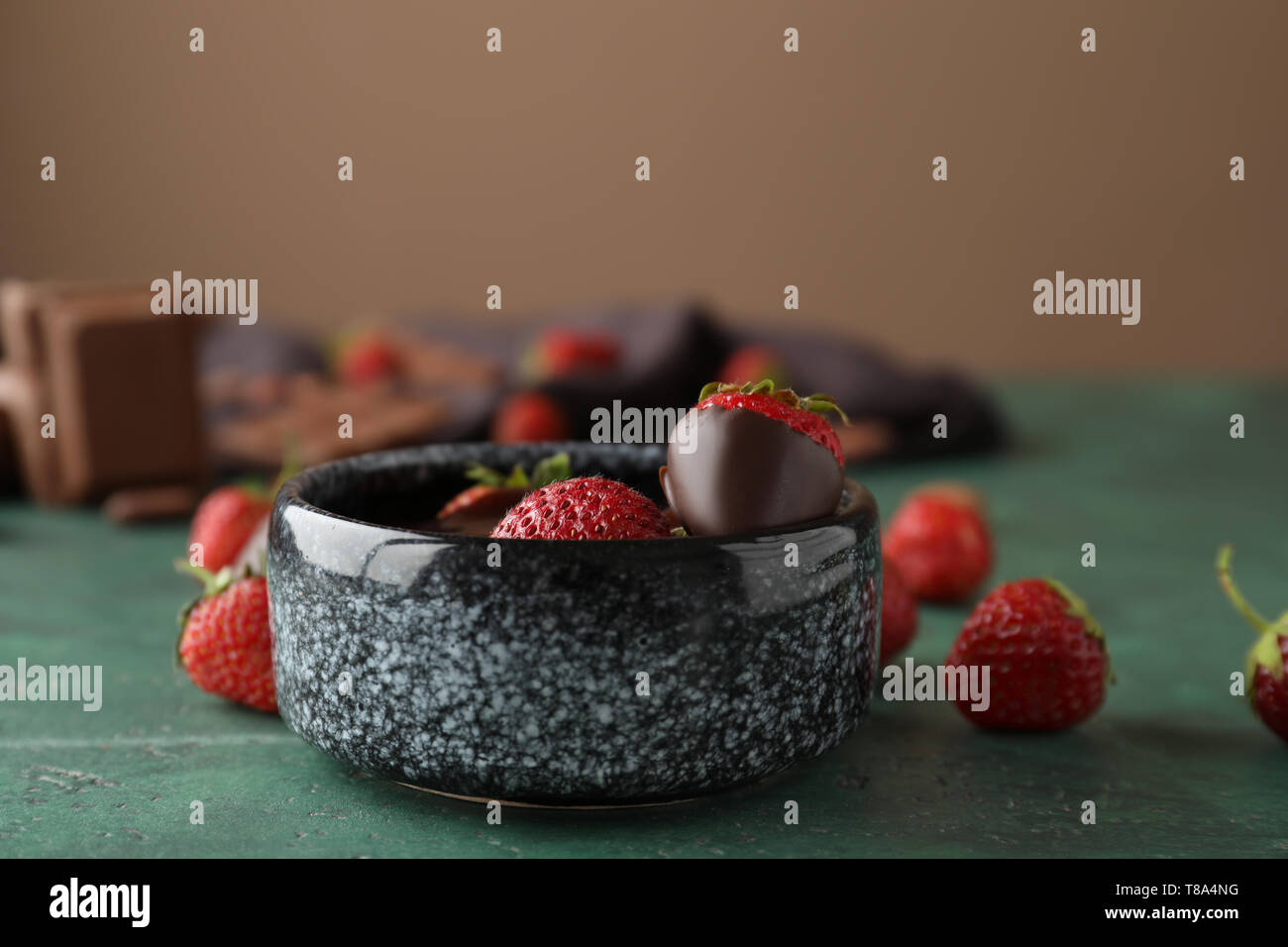 Pentola con cioccolato fuso e fragole mature sul tavolo verde Foto Stock