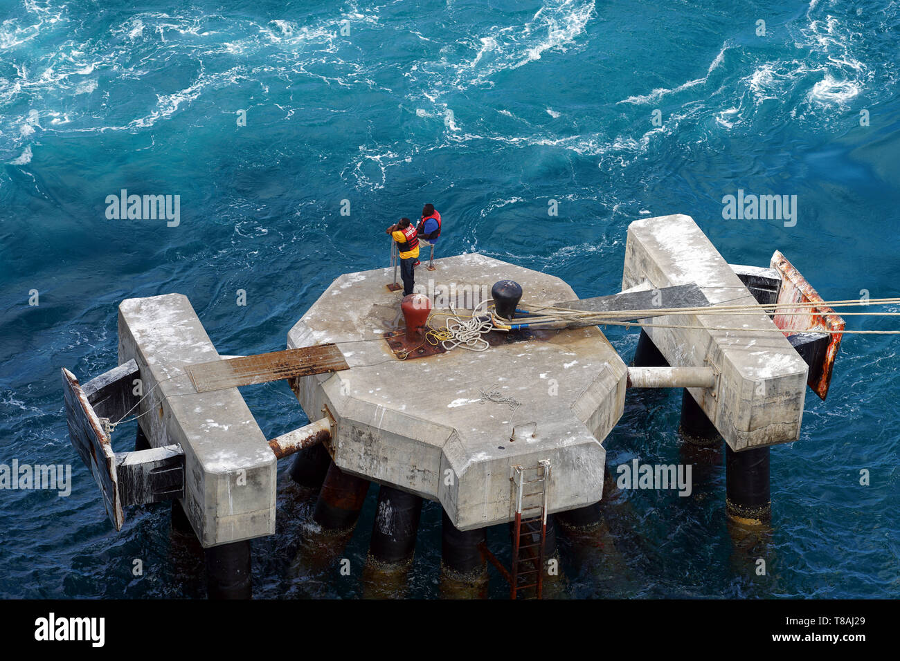 Lavoratori del molo in attesa di una nave da crociera ormeggiare presso l'ormeggio a Basseterre, St. Kitts. Foto Stock