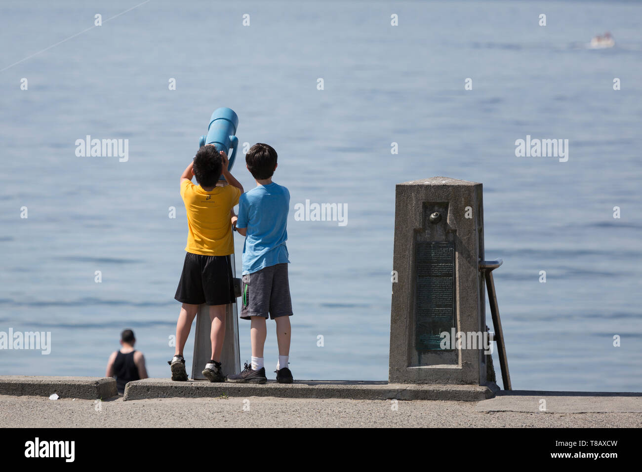 Seattle, Washington: due ragazzi di noi un monoculare per visualizzare le barche che passa lungo la spiaggia di Alki in West Seattle come la città si affaccia record di calore per il secondo giorno consecutivo. Foto Stock